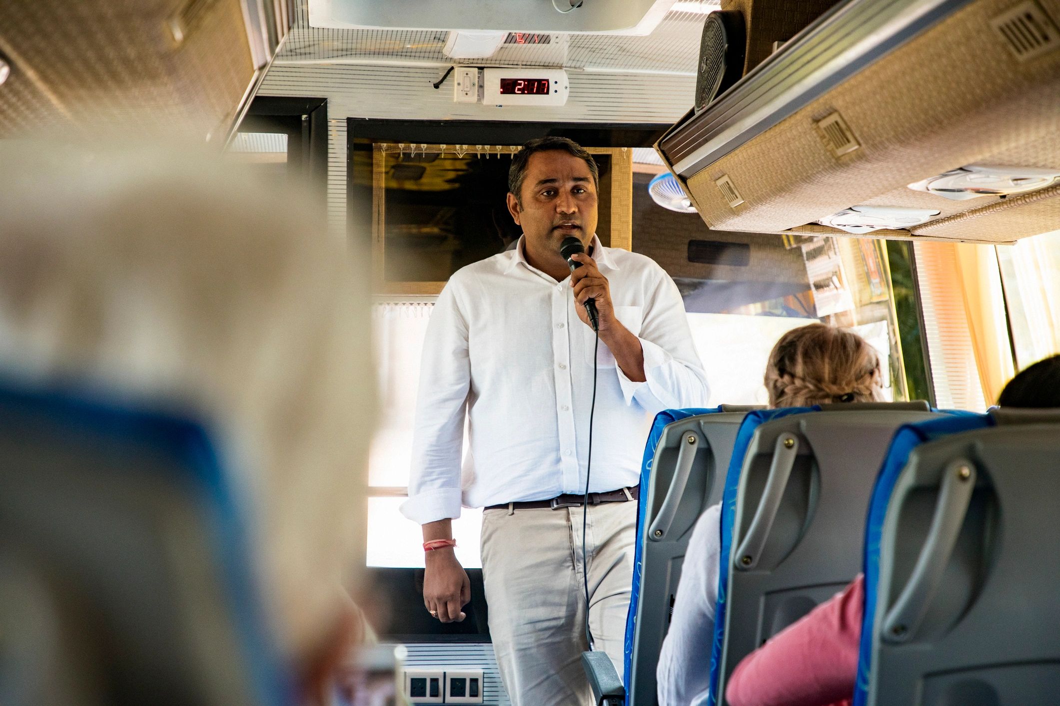 Guide talking to tourists on a coach bus
