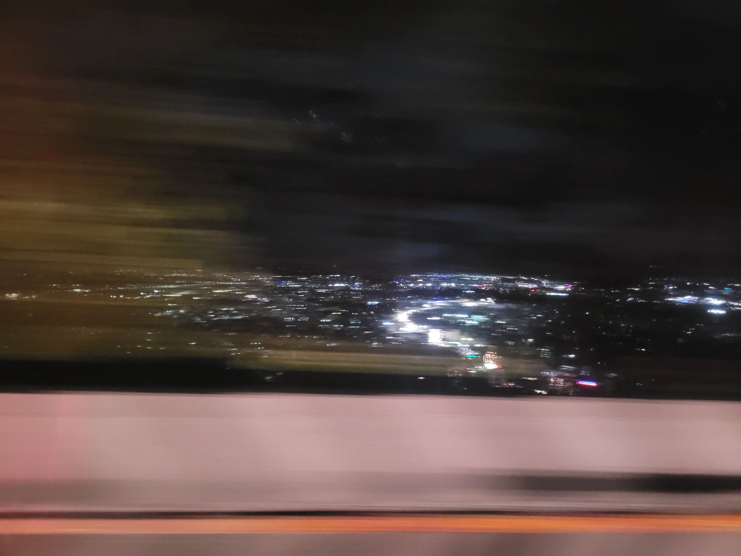 Blurred night view of city lights from hilltop road